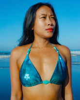 Woman in a blue bikini standing on a beach with a clear blue sky.