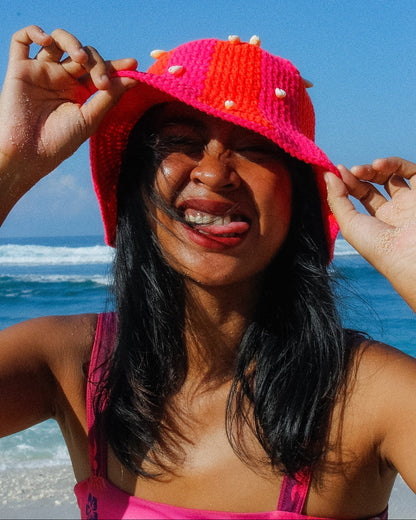 Woman wearing a bright pink hat with a blue ocean background